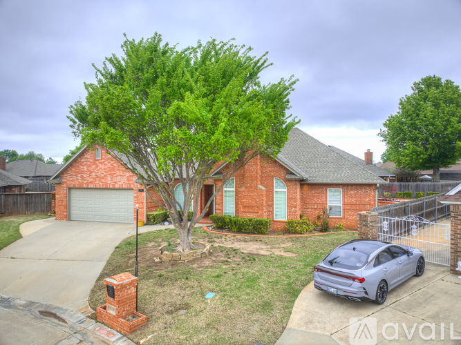 A house with a tree in front and a car parked in the driveway.