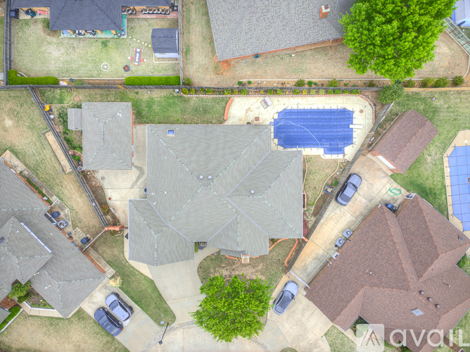 A bird's eye view of a neighborhood with houses, cars, and a swimming pool.