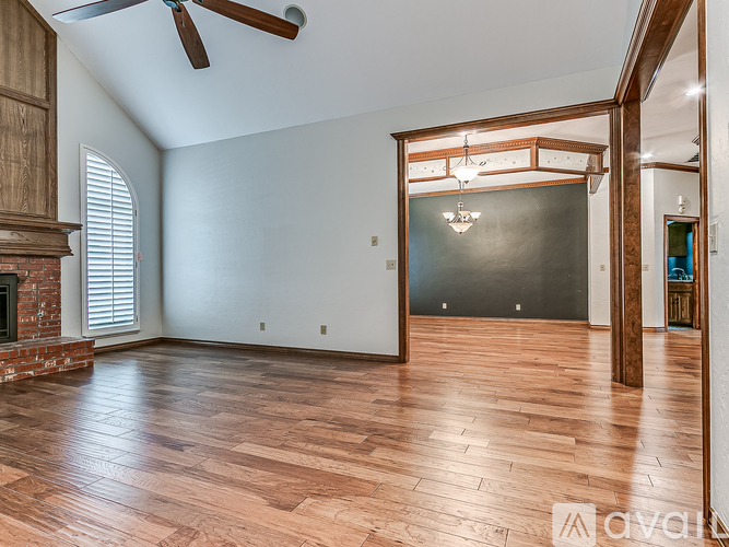 A spacious room with wooden flooring and a ceiling fan.