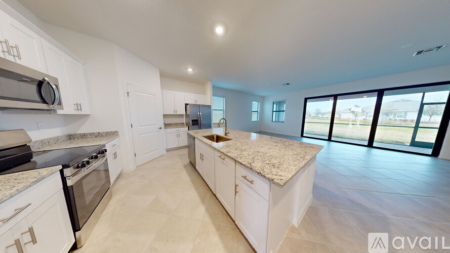 A spacious kitchen with white cabinets and a marble countertop.