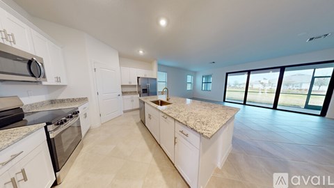 A spacious kitchen with white cabinets and a marble countertop.