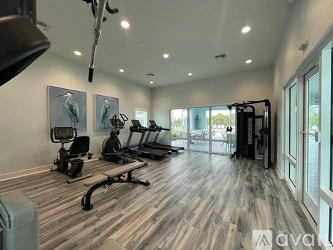 A well-lit gym with a variety of equipment including treadmills, stationary bikes, and weight machines.