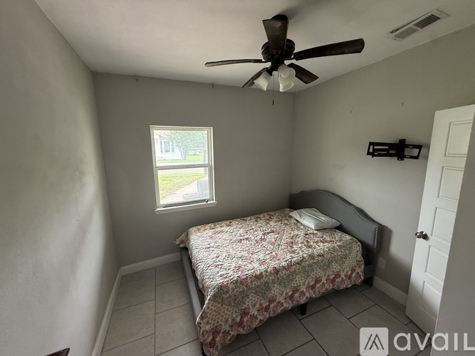 A bedroom with a bed, a window, and a ceiling fan.