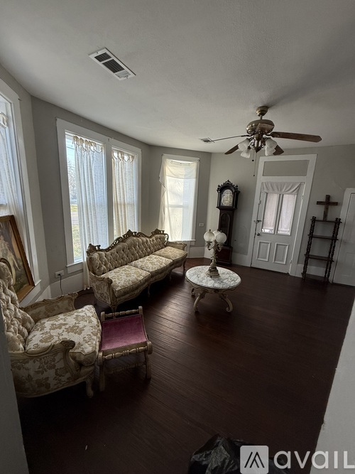 A living room with antique furniture and a ceiling fan.