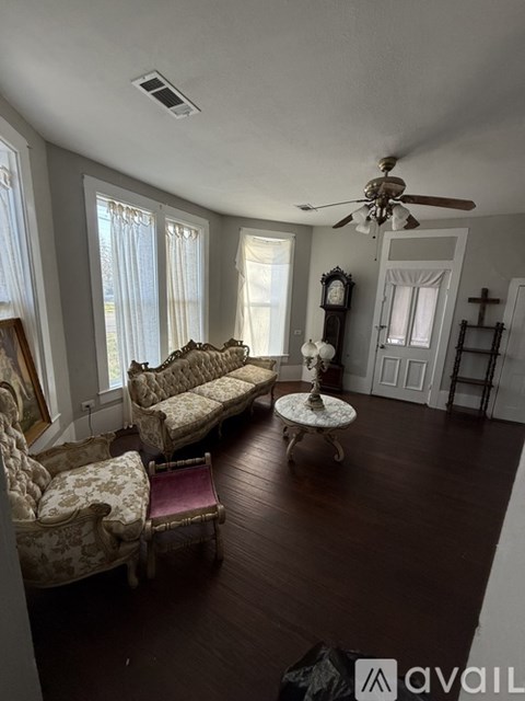 A living room with antique furniture and a ceiling fan.