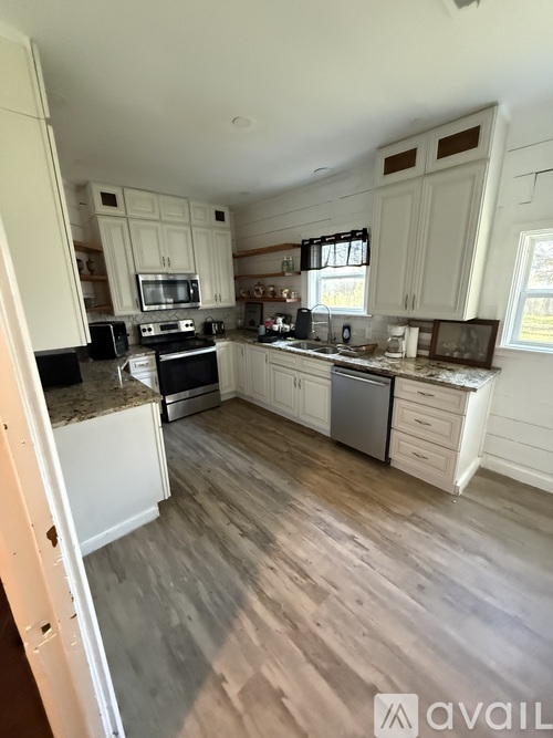 A kitchen with white cabinets and a wooden floor.