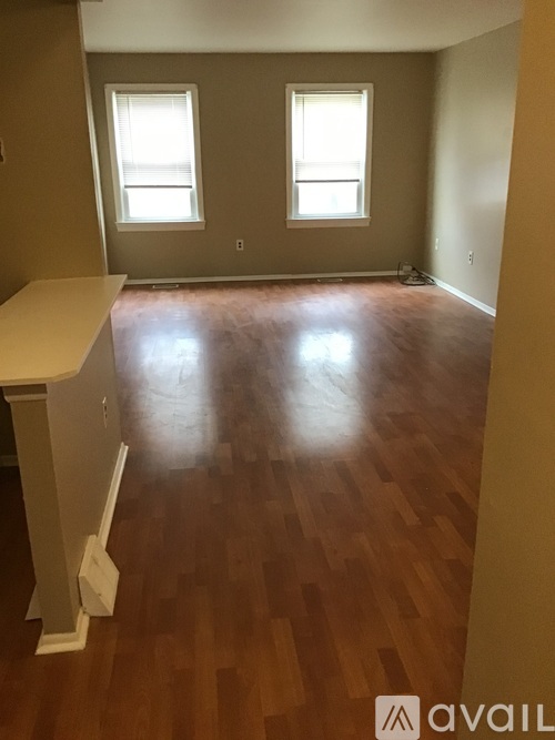 A room with wooden floors and two windows.