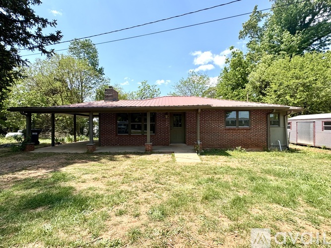 A red brick house with a porch and a green lawn.