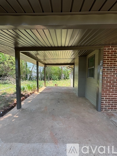 A covered walkway with a brick wall on one side and a metal pole on the other.