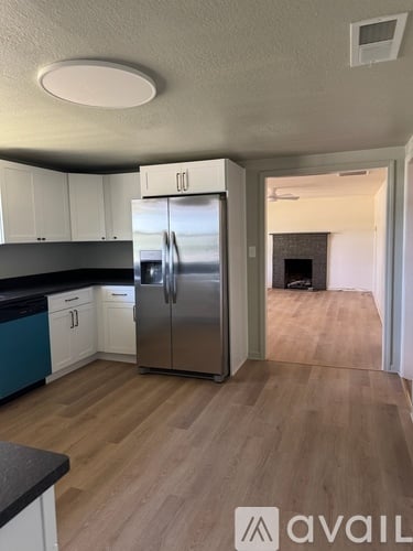 A kitchen with a stainless steel refrigerator and wooden flooring.