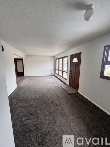 A carpeted room with a door and a window.