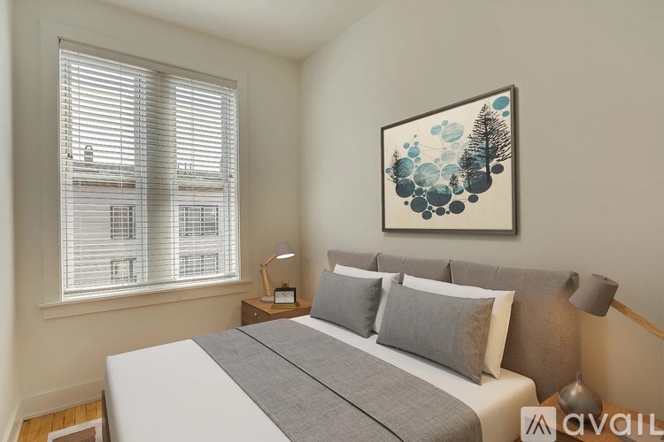 A bedroom with a large bed, a window with blinds, and a framed picture on the wall.