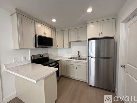 A kitchen with white cabinets and a stainless steel refrigerator.