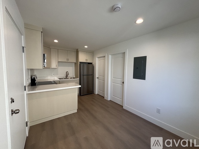 A kitchen with white walls and wooden floors is available for rent.