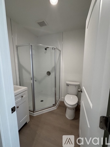 A white bathroom with a toilet, sink, and shower.