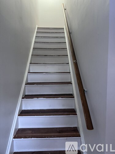 A staircase with a wooden handrail and white steps.