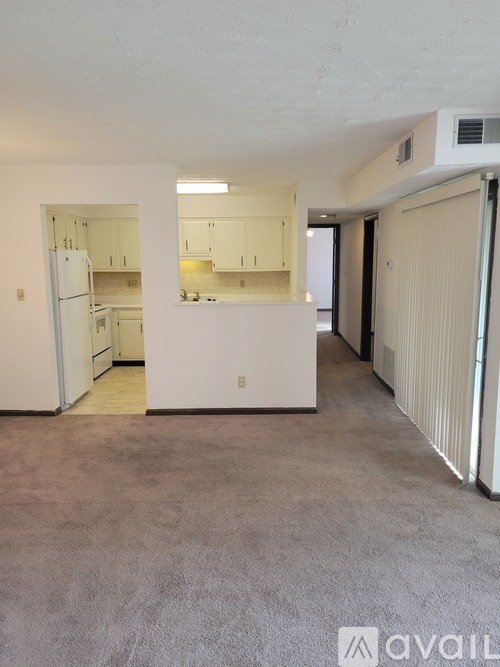 A spacious, empty room with a kitchen area in the background.