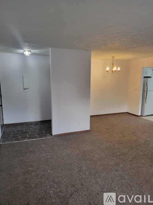A room with a carpeted floor and a chandelier hanging from the ceiling.