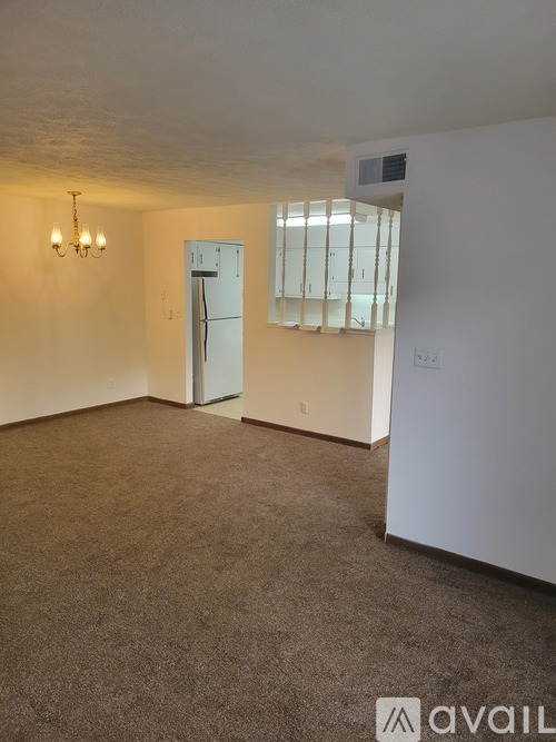 A carpeted room with a door and a chandelier.