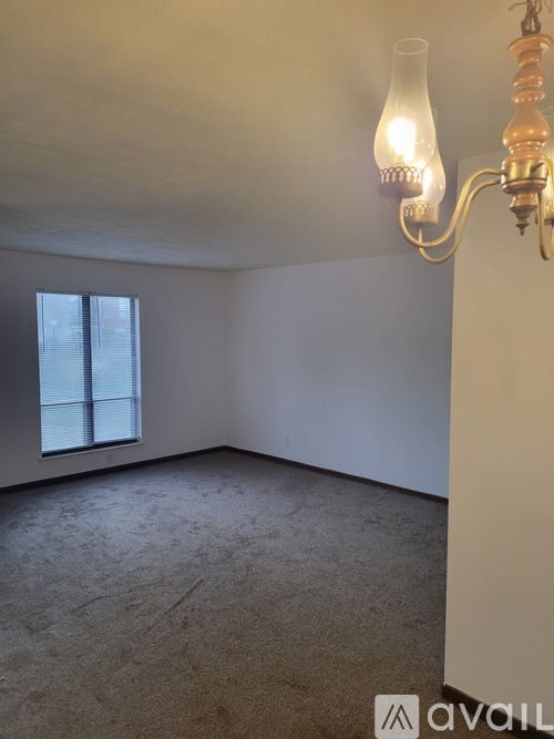 A room with a carpeted floor, a window, and a chandelier.
