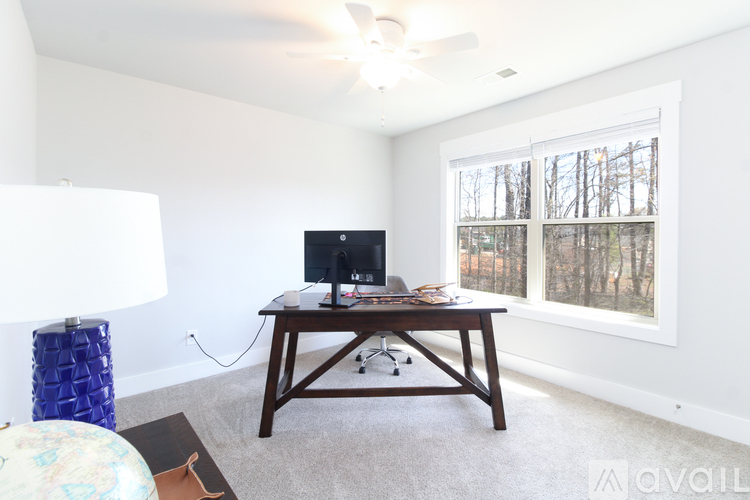 A room with a desk and a window showing trees outside.