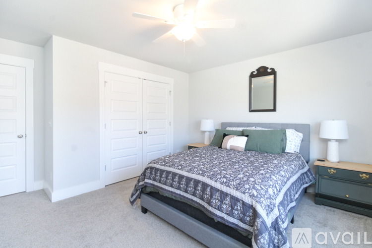 A bedroom with a bed, two lamps, and a mirror on the wall.