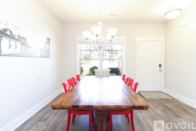 A dining room with a wooden table and red chairs.