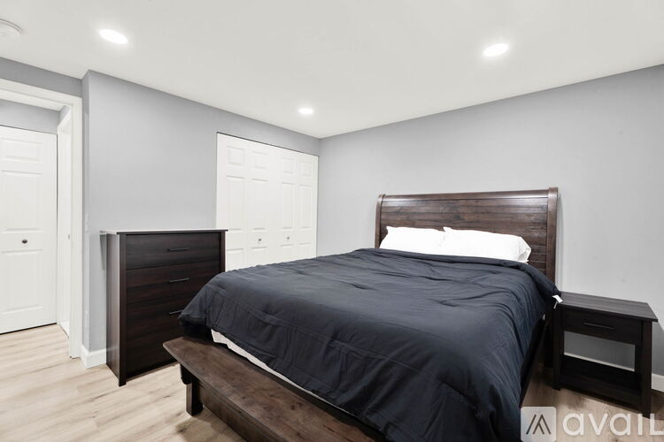 A bedroom with a dark bed and a wooden headboard.