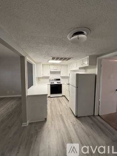 A kitchen with white cabinets and a wooden floor.