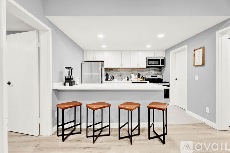A kitchen with white cabinets and a bar area with stools.