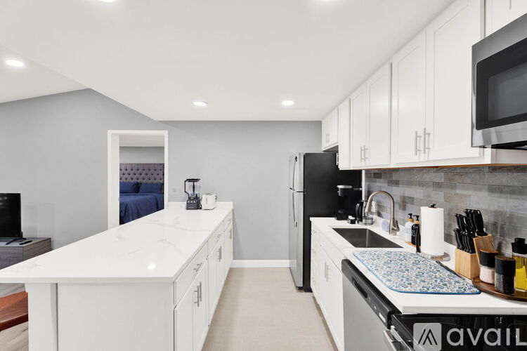 A kitchen with white cabinets and a black fridge.