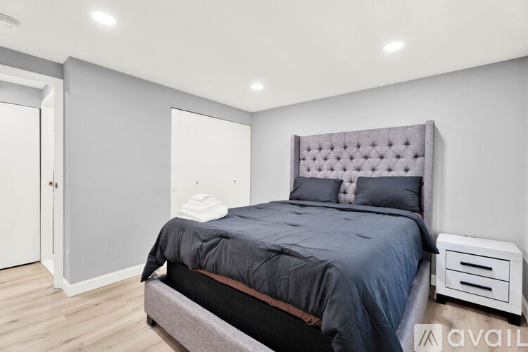 A bedroom with a bed, nightstand, and a wall-mounted air conditioner unit.