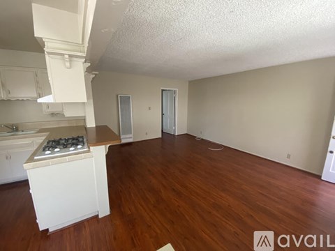 A kitchen with a stove top oven and wooden floors.