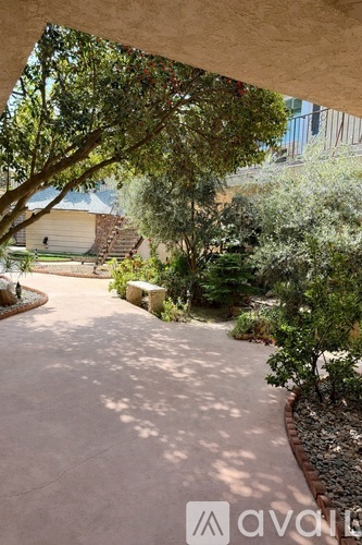 A garden pathway surrounded by greenery and a house in the background.