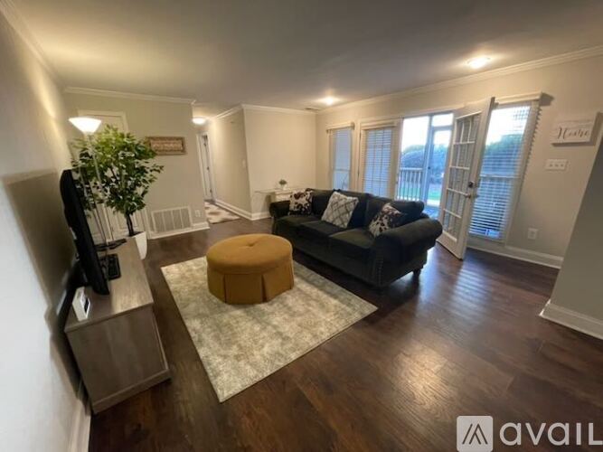 A living room with a black couch and a wooden floor.