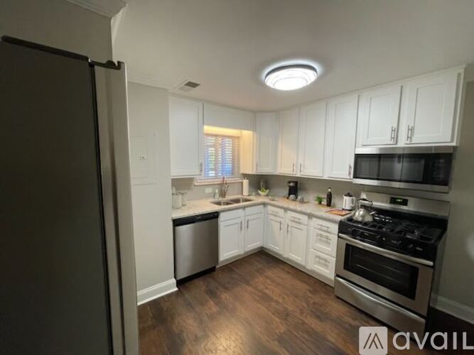 A kitchen with white cabinets and a wooden floor.