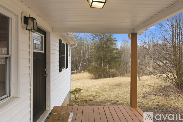 A porch with a wooden floor and a white wall.