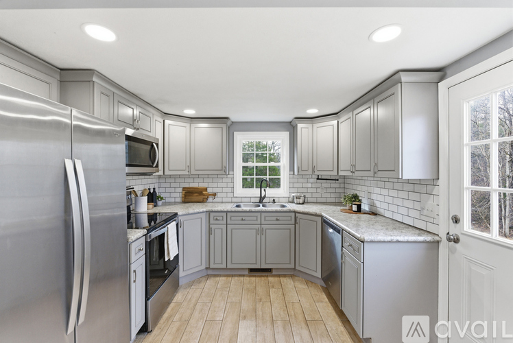 A modern kitchen with a refrigerator on the left and a sink in the middle.