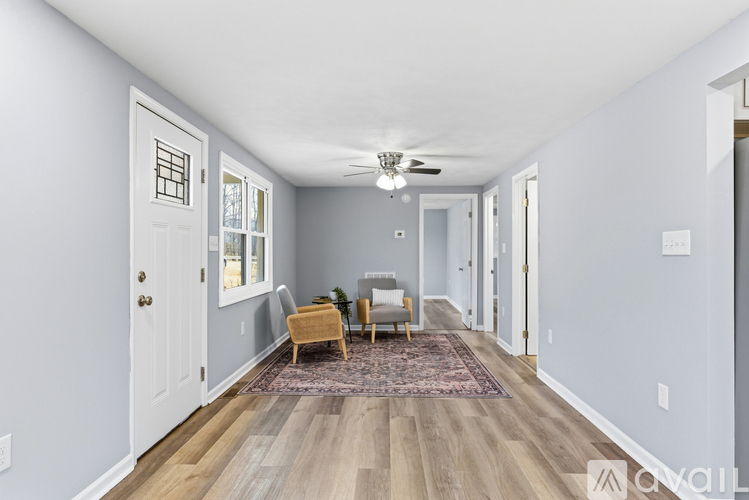 A spacious hallway with a rug and chairs.