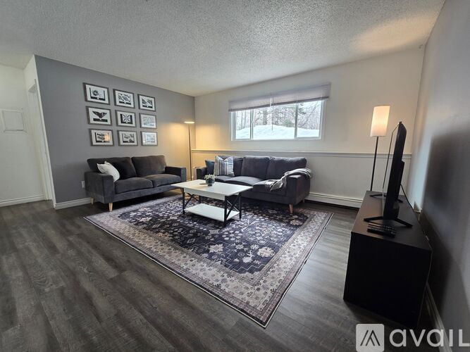 A living room with a grey couch, a black coffee table, and a large window.