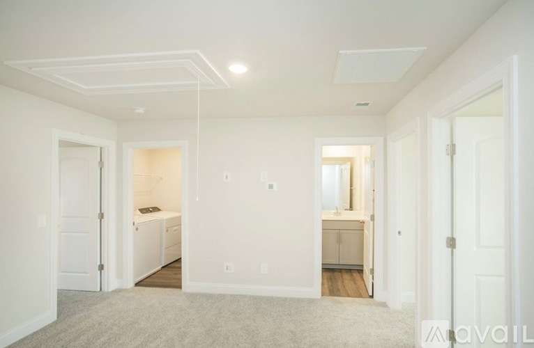 A spacious, empty room with white walls and a carpeted floor.
