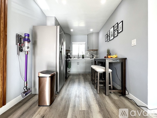 A modern kitchen with a stainless steel refrigerator and a bar area with a stool.