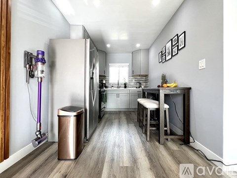A modern kitchen with a stainless steel refrigerator and a bar area with a stool.