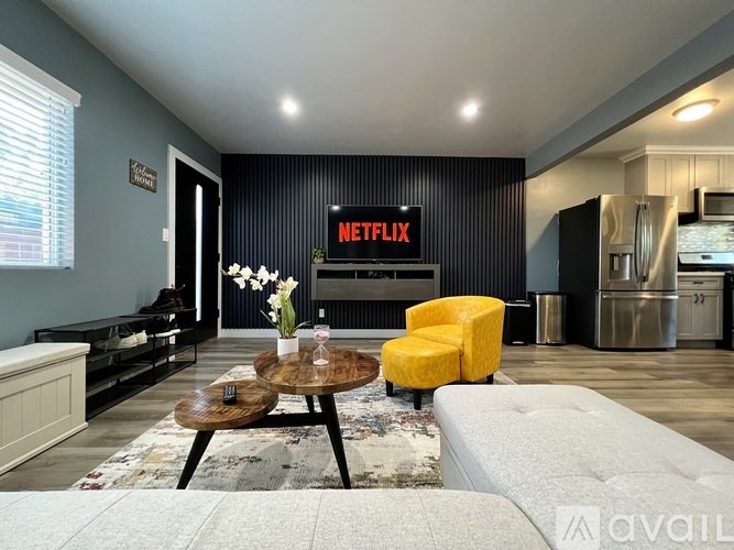 A living room with a white sofa, a wooden coffee table, and a yellow chair.
