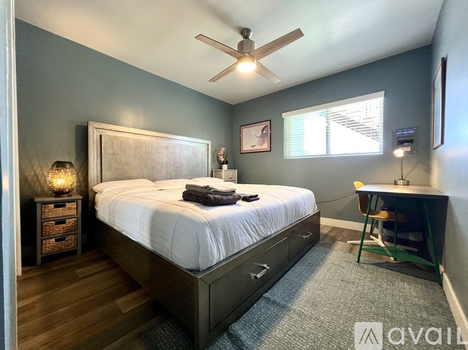 A bedroom with a large bed and a ceiling fan.