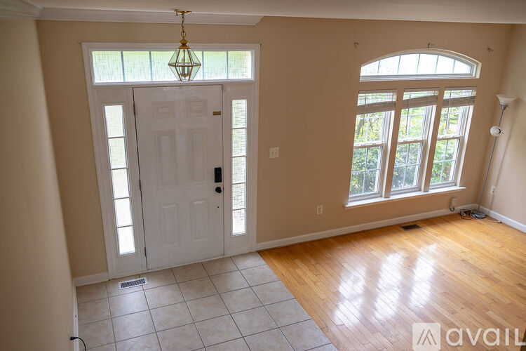 A room with a white door and a window with a view of trees.
