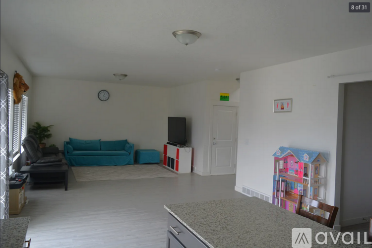 A living room with a sofa, a television, and a clock on the wall.