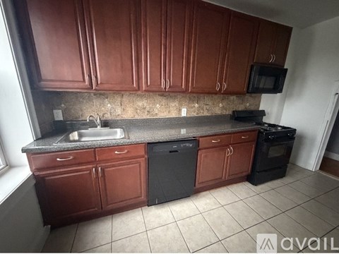 A kitchen with brown cabinets and black appliances.
