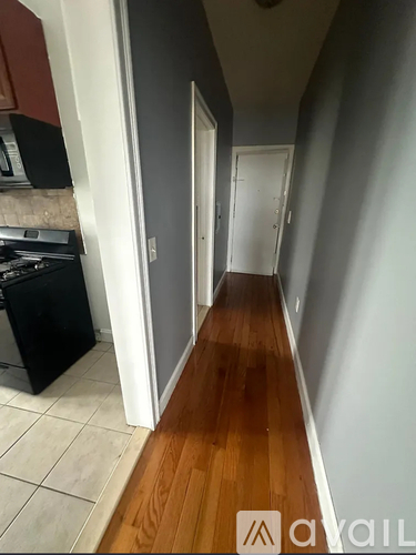 A long hallway with wood floors and white walls.