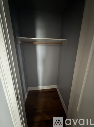 A small, empty room with a shelf and wooden floor.